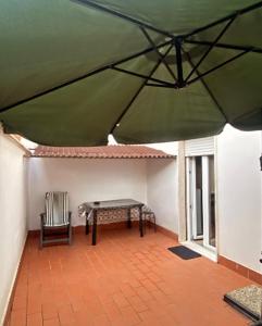 patio con tavolo e sedia sotto un ombrellone verde di Residenza Mazzini ad Avezzano