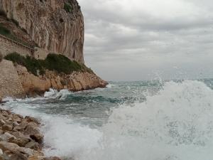 a wave in the ocean next to a cliff at Voilier tout confort in Beaulieu-sur-Mer