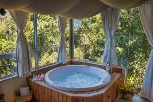 a large bath tub in a room with windows at Bombinhas Guest House in Bombinhas +194 photos