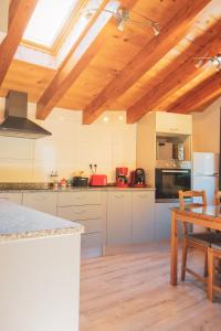 a large kitchen with wooden ceilings and a table at Casa amb molt encant i tranquilitat. in Ansalonga