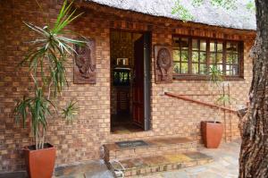 een bakstenen huis met twee planten ervoor bij Bona Ngwenya Lodge & Safaris in Marloth Park