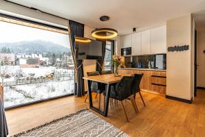 een keuken met een tafel met stoelen en een groot raam bij Aparthotel Zakopiański & SPA in Zakopane