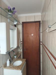 a bathroom with a wooden door and a sink at Quarto com Cama de Casal in Sorocaba