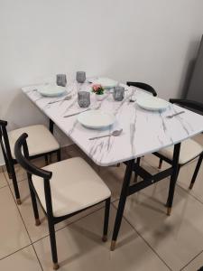 uma mesa branca com cadeiras e pratos em Cozy 2room 6pax @ Menara Sentral em Bukit Mertajam