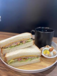 a sandwich and eggs on a plate with a cup of coffee at Fengjia JinRui Hotel in Taichung