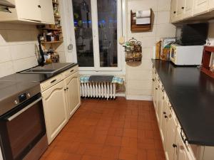una cocina con armarios blancos y encimeras negras en Maison JO 2024 en Guyancourt