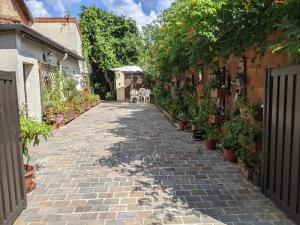 a cobblestone alley with two dogs and potted plants at Maison JO 2024 in Guyancourt