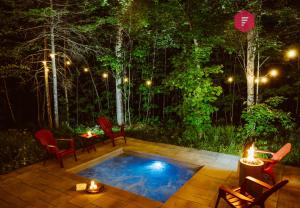 un patio con piscina di notte con sedie e candele di Le Céleste de Portneuf - Hot tub in the forest a Pont-Rouge