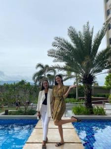 Deux femmes se tiennent à côté d'une piscine dans l'établissement Horizon101 studio gem, à Cebu