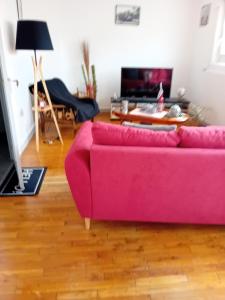 Sofá rosa en la sala de estar con mesa en Gîte les palmiers, en Guingamp