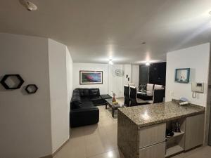 a living room with a black couch and a kitchen at apartamento completo en Cañaveral in Cañaveral