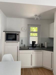 a white kitchen with a sink and a microwave at Apartment Nr. 2 Bad Laasphe Altstadt in Bad Laasphe