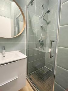 La salle de bains est pourvue d'une douche, d'un lavabo et d'un miroir. dans l'établissement Petite maison proche du métro, à Bagnolet