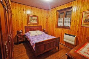 - une chambre avec un lit dans une pièce dotée de murs en bois dans l'établissement Fionisco - Giardino privato con vista sulle Alpi, à Brusson
