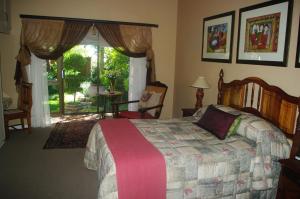 1 dormitorio con 1 cama y puerta a un patio en Primavera Guest House, en Bloemfontein