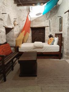 um quarto com uma cama e um banco num quarto em نزل كوفان التراثي Koofan Heritage Lodge em Salalah