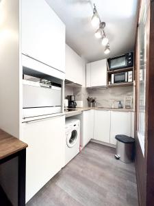 a kitchen with white cabinets and a washer and dryer at 1- Studio Brides-les-bains tout confort in Brides-les-Bains