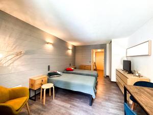 a bedroom with a bed and a table and a tv at 1- Studio Brides-les-bains tout confort in Brides-les-Bains