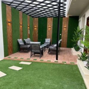 un patio con sillas, mesas y una pared verde en شاليهات دار الورد en Taif
