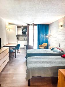a bedroom with a bed and a table and a kitchen at 1- Studio Brides-les-bains tout confort in Brides-les-Bains