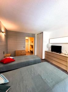 a bedroom with two beds and a flat screen tv at 1- Studio Brides-les-bains tout confort in Brides-les-Bains