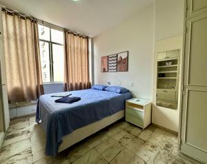 ein Schlafzimmer mit einem blauen Bett und einem Fenster in der Unterkunft Ótimo Apartamento - 500m Praia Copacabana/RJ in Rio de Janeiro