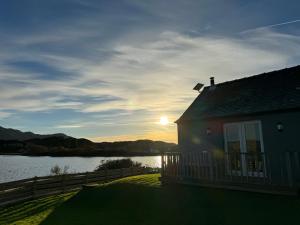 a house with a view of a lake and the sunset at Loch Morar Private Suite in Mallaig
