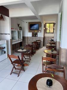 a restaurant with wooden tables and chairs and a tv at Pousada Maramar/terceira praia MSP in Morro de São Paulo