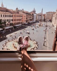 eine Person, die aus einem Fenster in eine Stadtstraße blickt in der Unterkunft Navona 49 Luxury Suites&Apartment in Rom