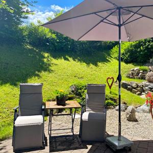 twee stoelen en een tafel met een paraplu bij Ferienwohnung Jochum-Pfeiffer in Riezlern