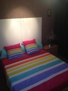 a bed with colorful blankets and pillows on it at Chambre d'hôtes l'Amaryllis in Cournon-dʼAuvergne