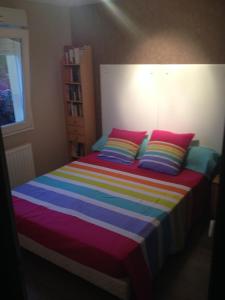 - un lit avec des oreillers colorés dans une chambre dans l'établissement Chambre d'hôtes l'Amaryllis, à Cournon-dʼAuvergne