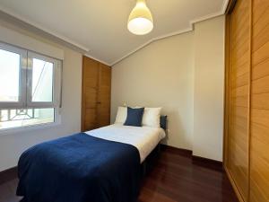 una camera da letto con un letto con una coperta blu e una finestra di Fantástico Dúplex Vista Bahia a El Astillero