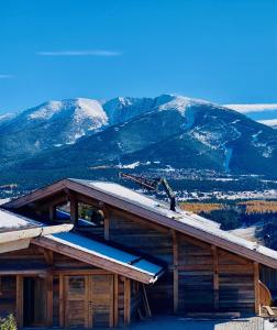 Cabaña de madera con nieve en el techo y las montañas en Chalet Aguila - Jacuzzi et sauna panoramique - Construit en 2023, en Bolquere Pyrenees 2000