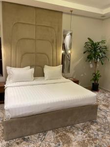 1 dormitorio con 1 cama grande con sábanas blancas en شاليهات دار الورد en Taif