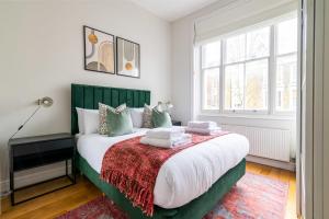 um quarto com uma cama com uma cabeceira verde em Fantastic Earls Court Flat em Londres