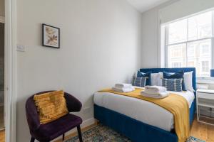 um quarto com uma cama e uma cadeira em Fantastic Earls Court Flat em Londres