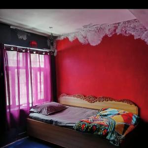 a bedroom with a red wall and a bed at Wild Homestay in Baragrān