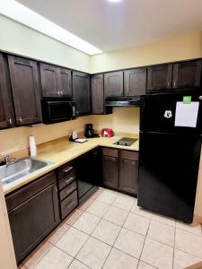 cocina con armarios de madera y nevera negra en lovely entire Suite with kitchen 5 Min to Disney, en Orlando