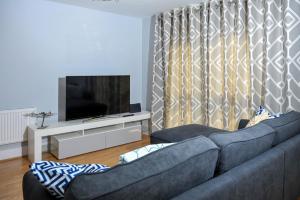 een woonkamer met een blauwe bank en een tv bij The Pavilions by Select SA in Windsor