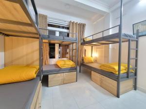 Habitación con 2 literas y sábanas amarillas. en Tiny Tigers Hostel en Da Lat