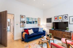 a living room with a blue couch and a tv at Stunning Earls Court Flat in London