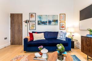 a living room with a blue couch and a table at Stunning Earls Court Flat in London
