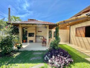 Ein Haus mit einer Terrasse mit einem Tisch und Stühlen in der Unterkunft Linda casa frente a lagoa! in Laguna