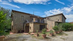 a brick house with a balcony and potted plants at Il Pascolo in San Gimignano
