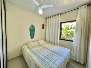 een slaapkamer met een bed en een plafondventilator bij Linda casa frente a lagoa! in Laguna