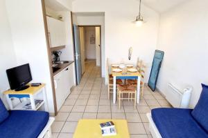 een kleine woonkamer met een tafel en een keuken bij "SOLEIL DU GOLF" Appartement 5 personnes, vue golf, accès parc aquatique in Talmont