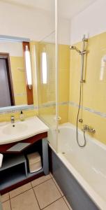 een badkamer met een bad, een wastafel en een douche bij "SOLEIL DU GOLF" Appartement 5 personnes, vue golf, accès parc aquatique in Talmont