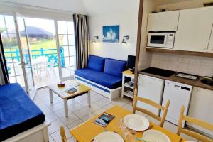 een kleine keuken en een woonkamer met een blauwe bank bij "SOLEIL DU GOLF" Appartement 5 personnes, vue golf, accès parc aquatique in Talmont