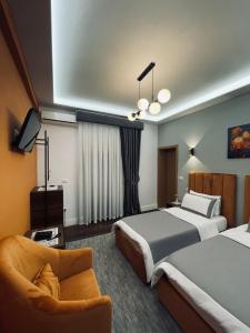 una habitación de hotel con 2 camas y una silla en Garden Boutique Hotel, en Elbasan